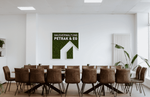 Der Besprechungsraum mit großem Tisch, vielen Stühlen und dem Firmenlogo an der Wand.