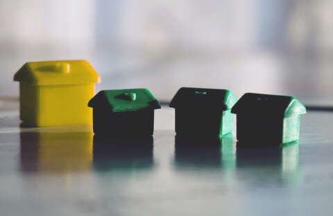 Ein Hotel und drei Häuser aus Monopoly, aber in Gelb und Grün.