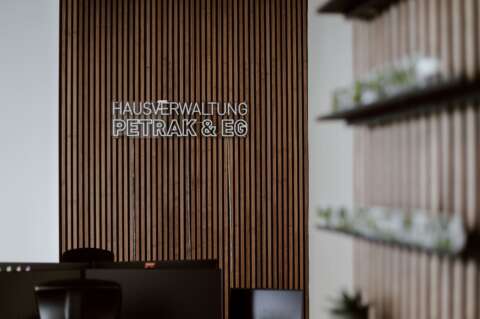 Arbeitszimmer mit Leuchtschritzug an der Wand, Monitore auf Schreibtischen im Anschnitt.