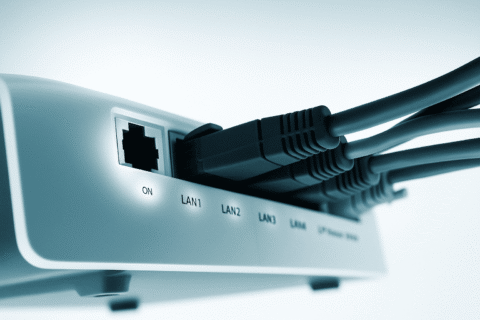 Ein weißer Router in dem mehrere Kabel stecken.